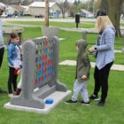 Family playing giant Connect Four game in park.