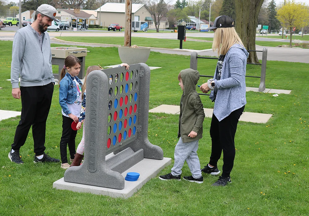Family playing giant Connect Four game in park.