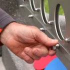 Hand turning a knob on a metal object.