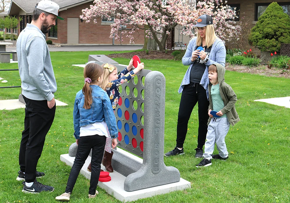 Family playing giant Connect Four in a park.