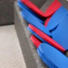 Blue and red plastic seats stacked on a concrete surface.