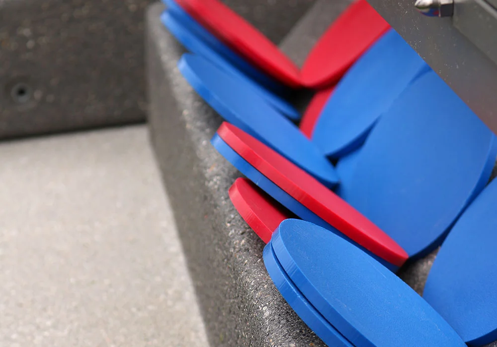 Blue and red plastic seats stacked on a concrete surface.