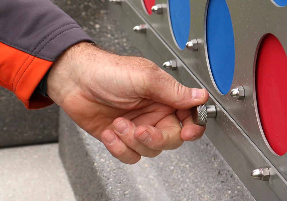 Hand adjusting a knob on a playground structure.