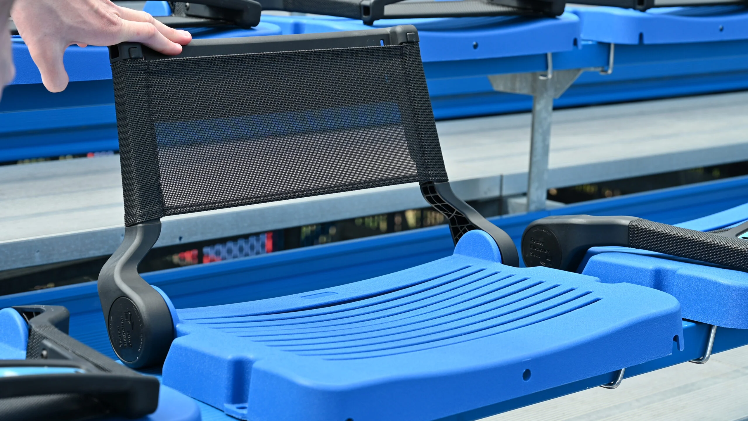Blue stadium seat with mesh back and footrest.