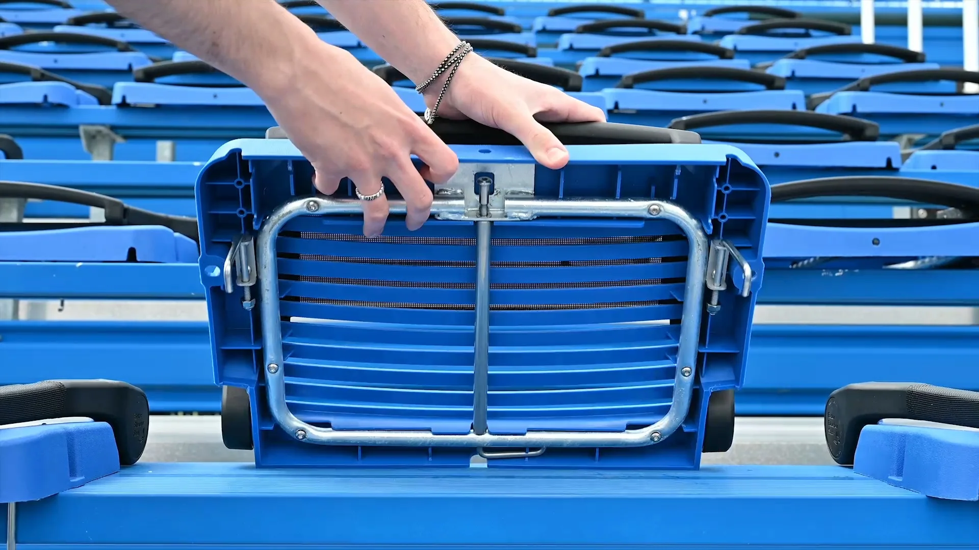 Blue folding chair being adjusted in a stadium.