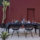 Modern outdoor dining table and chairs in front of a red building.
