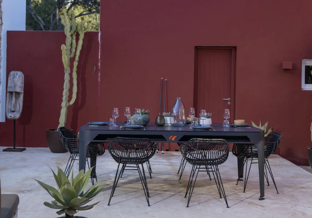 Modern outdoor dining table and chairs in front of a red building.