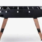 Foosball table with black top and wooden legs.