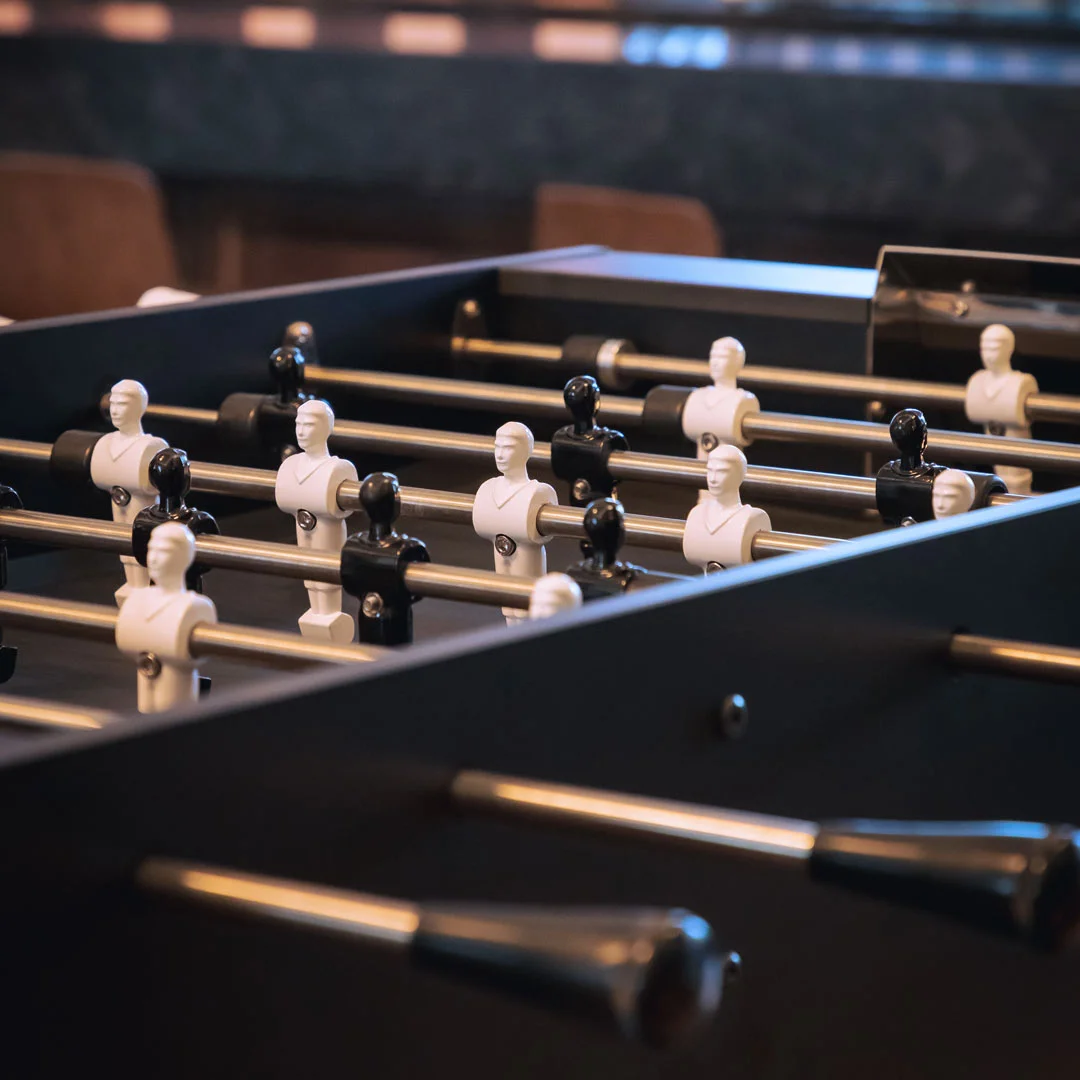 Foosball table with white figures and black rods.