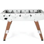 Foosball table with white top and wooden legs.