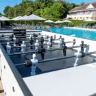 Outdoor foosball table by a pool.