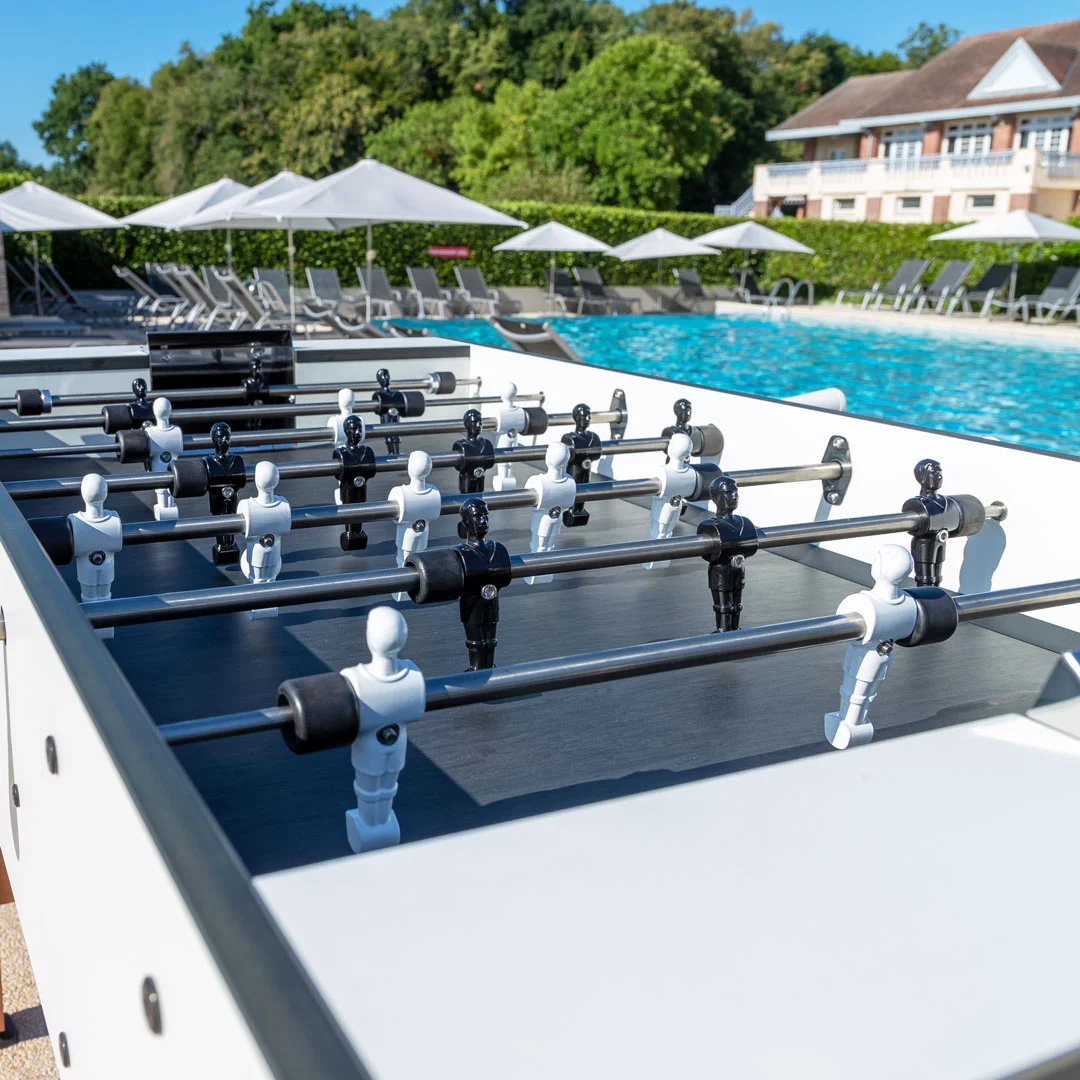 Outdoor foosball table by a pool.