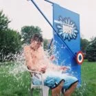 A person sitting in a chair being sprayed by a water gun.