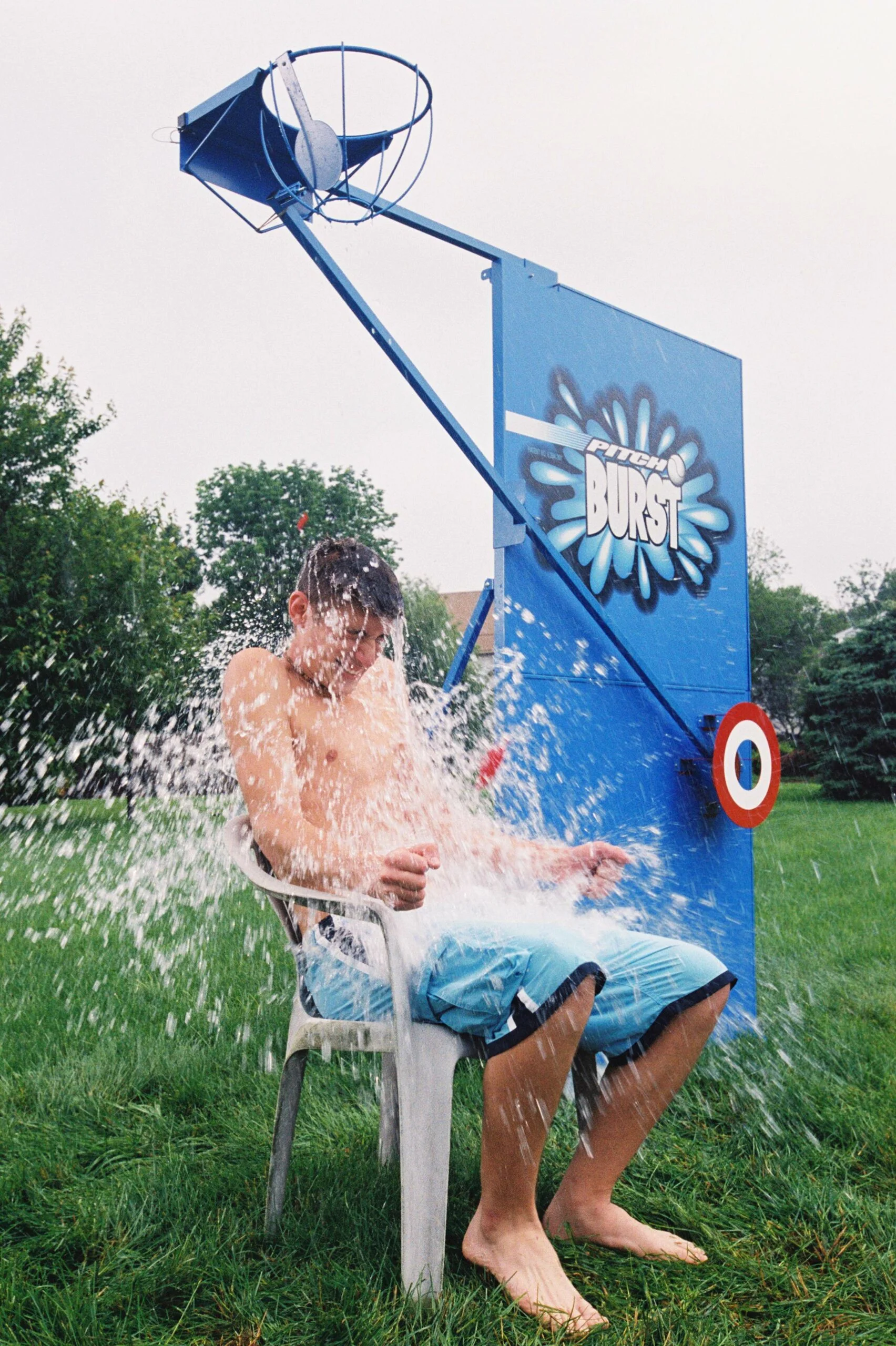 A person sitting in a chair being sprayed by a water gun.