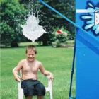 Boy sitting in chair under a blue water spout.