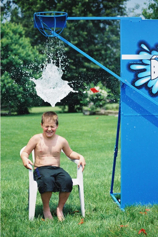 Boy sitting in chair under a blue water spout.