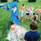 Girl sliding down a water slide while others watch.