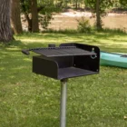 Portable grill on grass near a river.