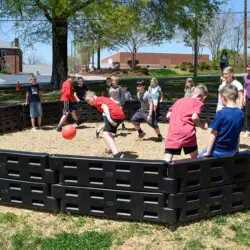 Children playing in a playground with black plastic crates.