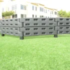 Stacked black plastic containers on green grass.