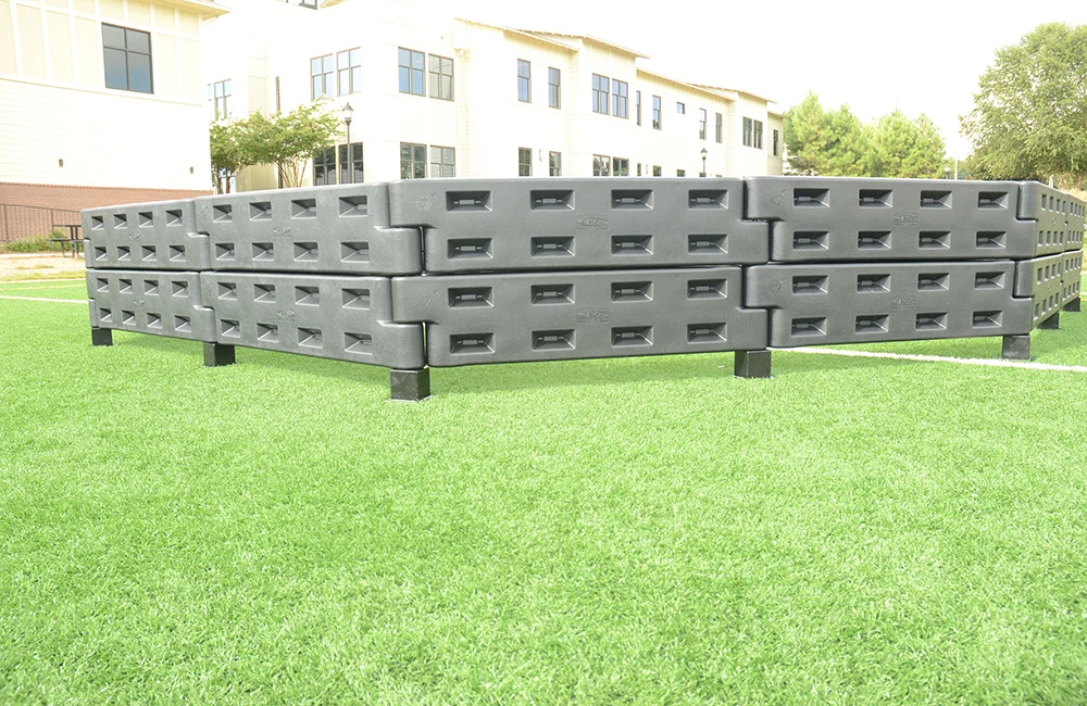 Stacked black plastic containers on green grass.
