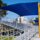 Outdoor bleachers with blue shade sails and yellow poles.
