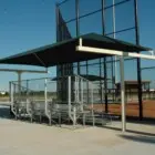 Baseball dugout with green roof and metal seating.