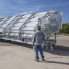 Man standing next to a trailer loaded with metal sheets.