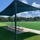 Outdoor sports field with shade structure and seating area.
