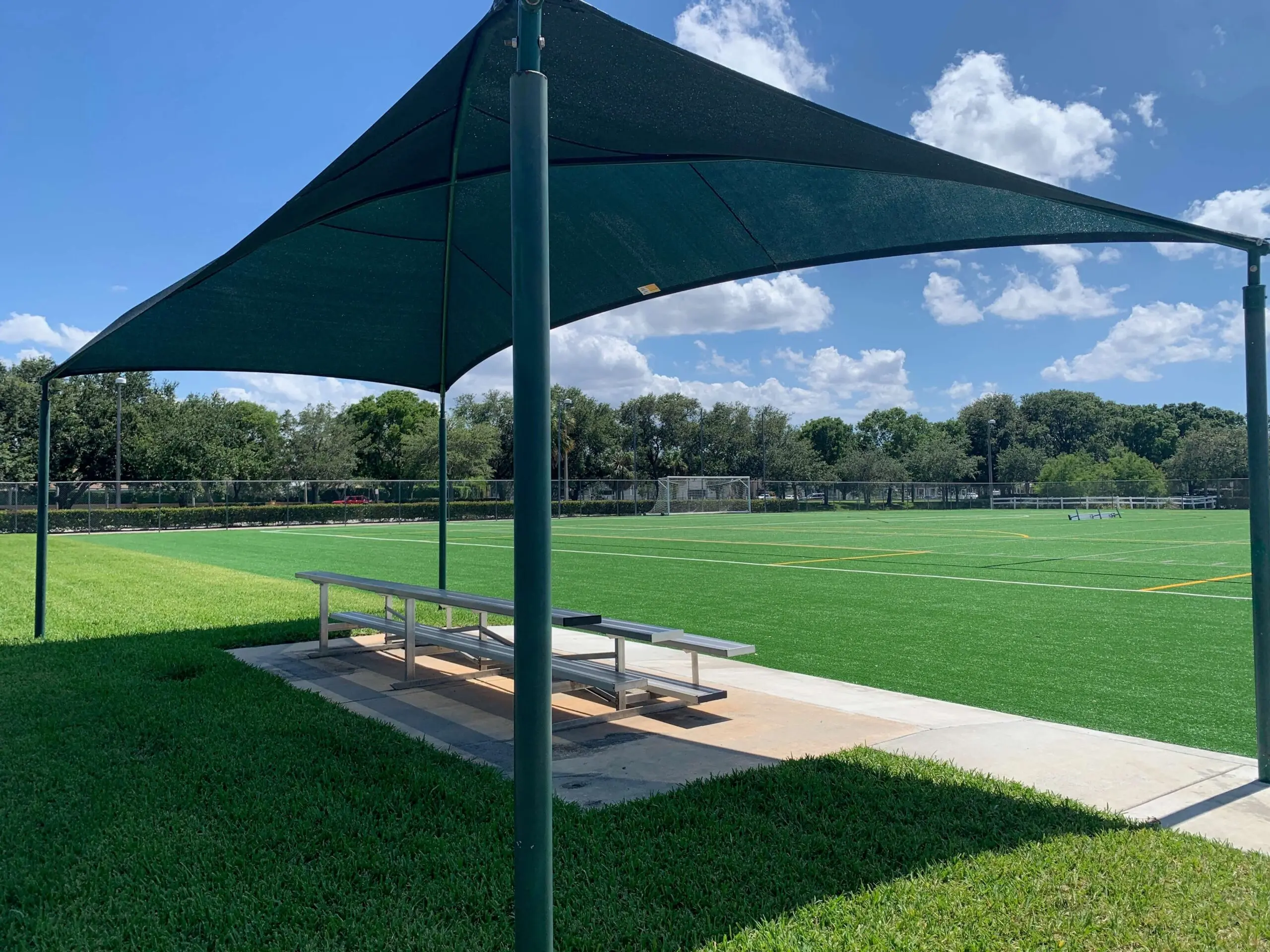 Outdoor sports field with shade structure and seating area.