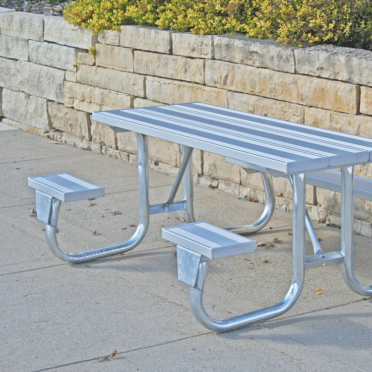 6J2GA-SWC Outdoor picnic table with metal benches and a stone wall in the background.
