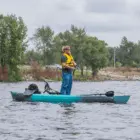Man fishing from a kayak on calm water.