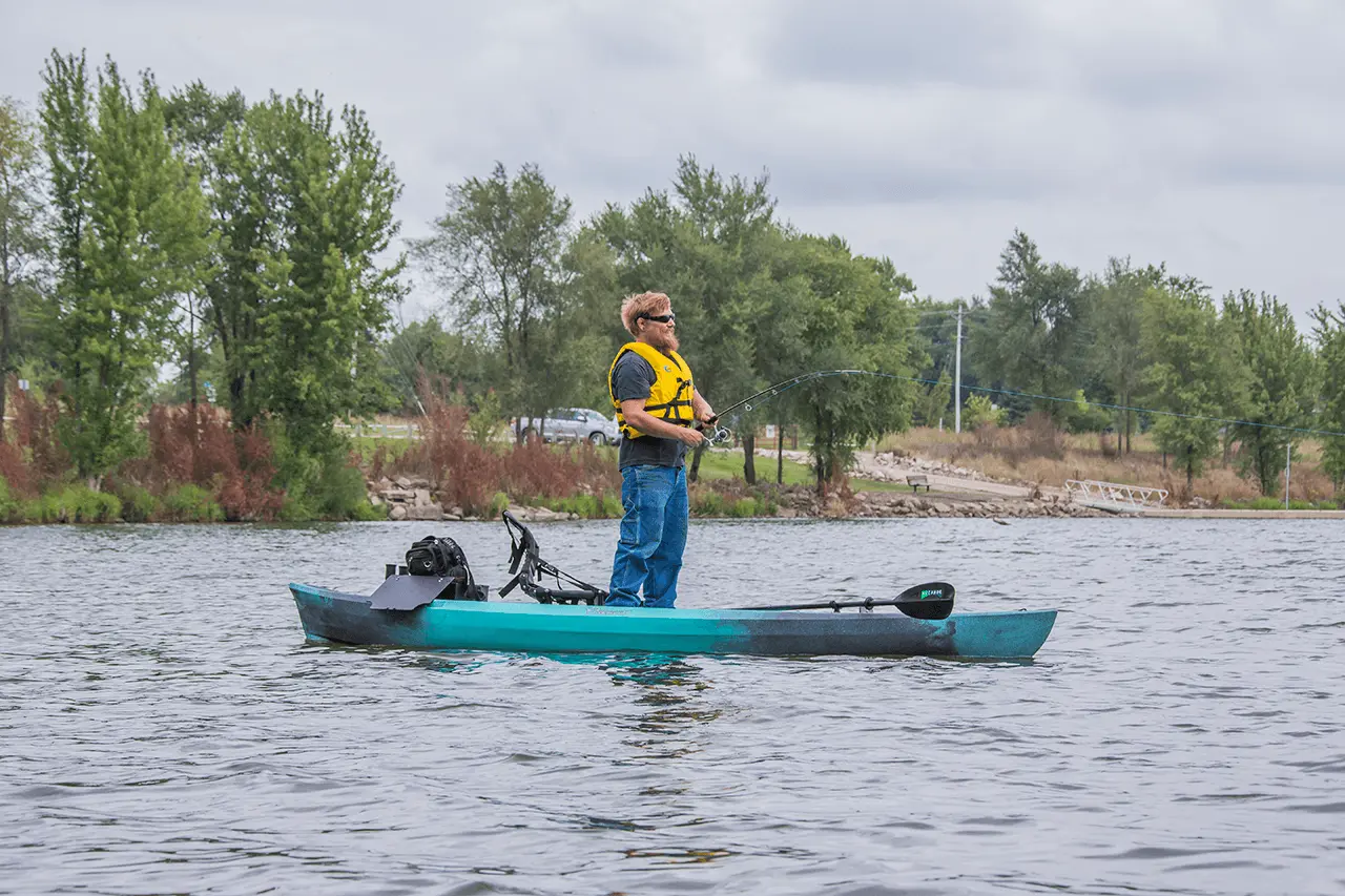 Man fishing from a kayak on calm water.