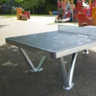 Outdoor ping pong table in a playground setting.