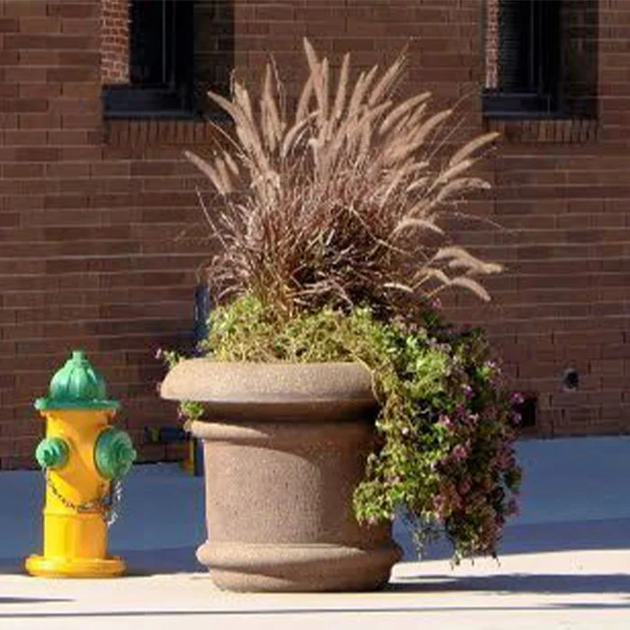 A colorful outdoor scene featuring a beige planter with tall grasses and flowers next to a yellow fire hydrant.