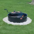 Outdoor fire pit with grill on a grassy lawn.