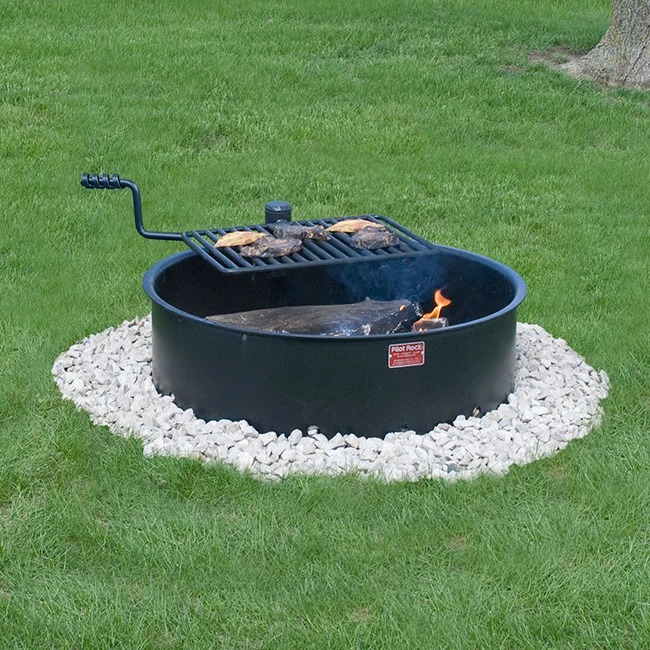 Outdoor fire pit with grill on a grassy lawn.