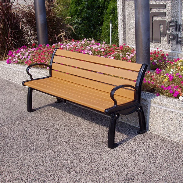 JPAB-Recycled-Bench Wooden bench on a sidewalk near flowers.