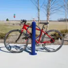 Red bicycle parked on a blue bike rack in an outdoor setting.