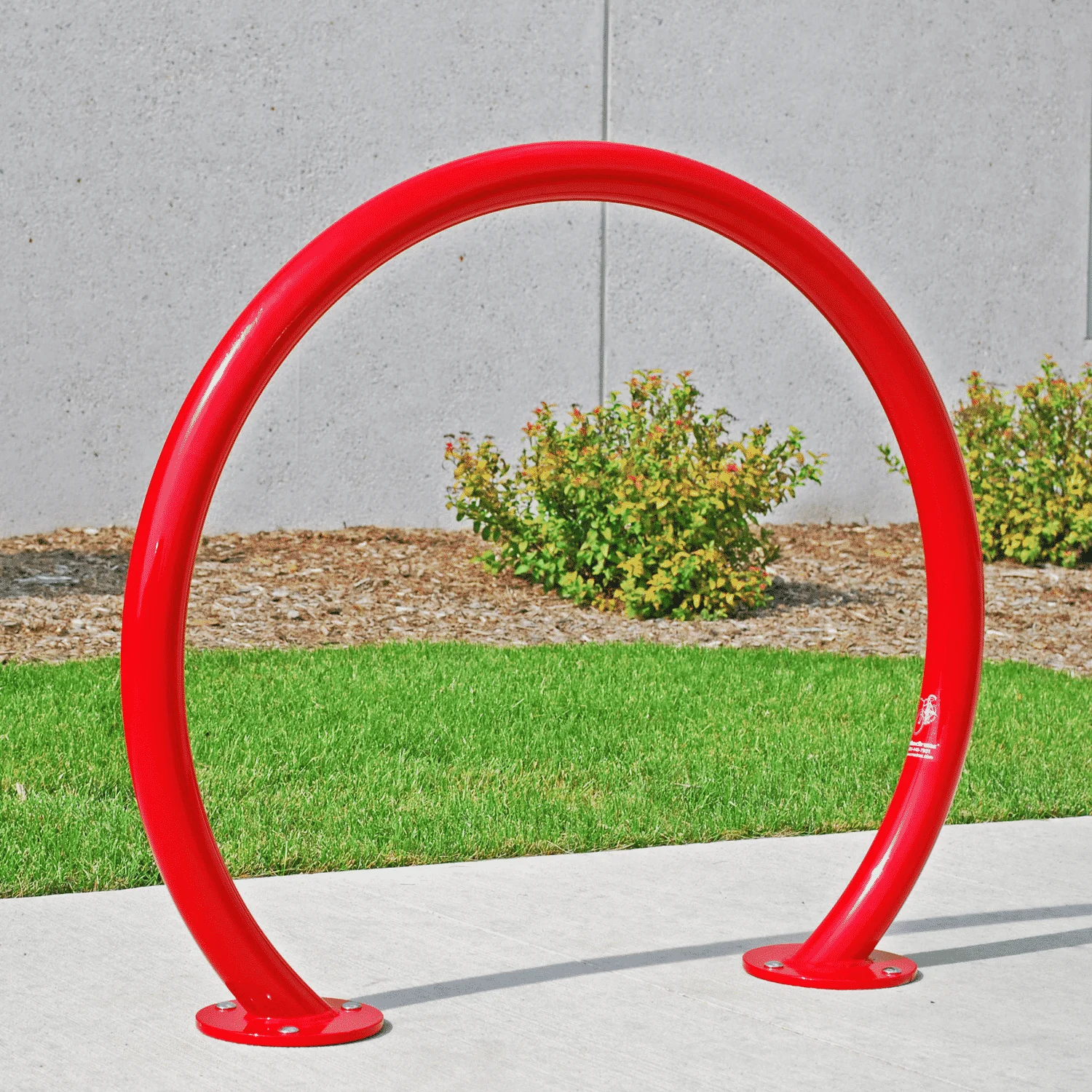 Red bicycle rack on concrete sidewalk.