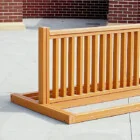 Wooden deck railing in front of a brick wall.