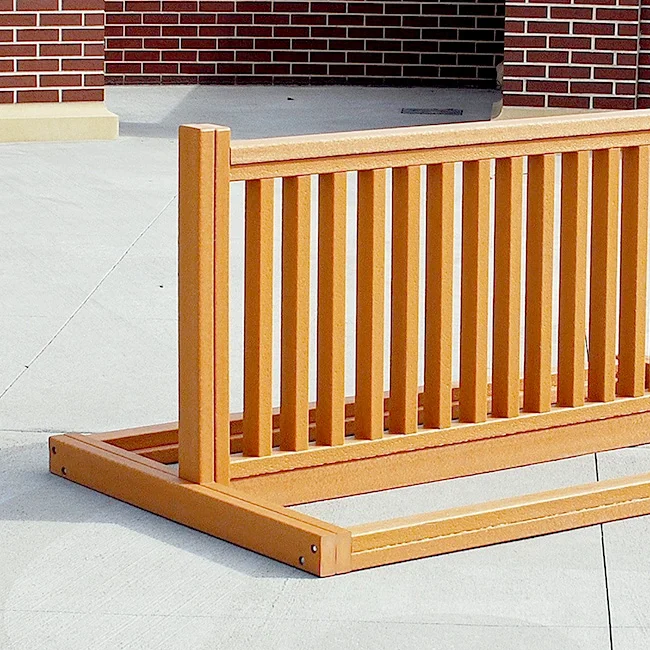 PB-6CEDBIKE Wooden deck railing in front of a brick wall.