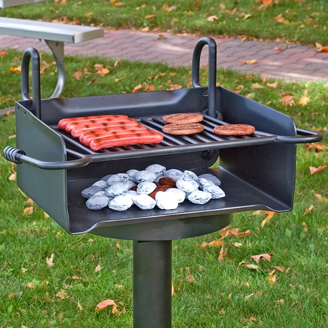 Portable grill with hot dogs and cookies cooking on a grassy outdoor area.