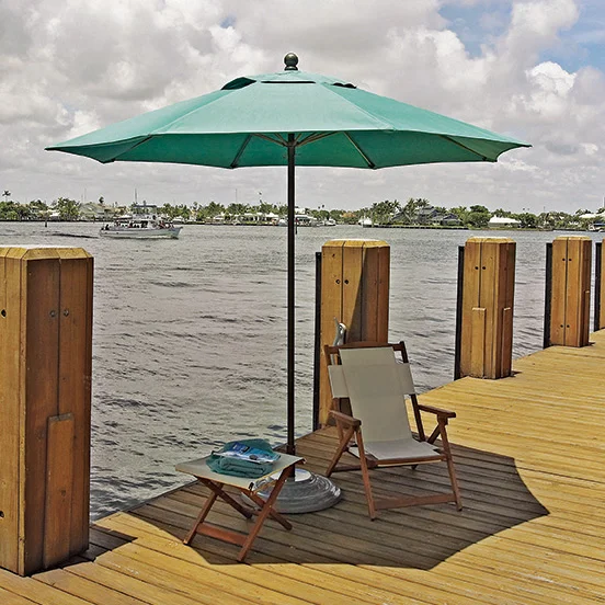 UOM7MU-SeaGreen Umbrella and lounge chair on a wooden dock by the water.