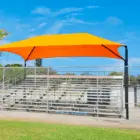 Baseball stadium seating area with a colorful shade structure.