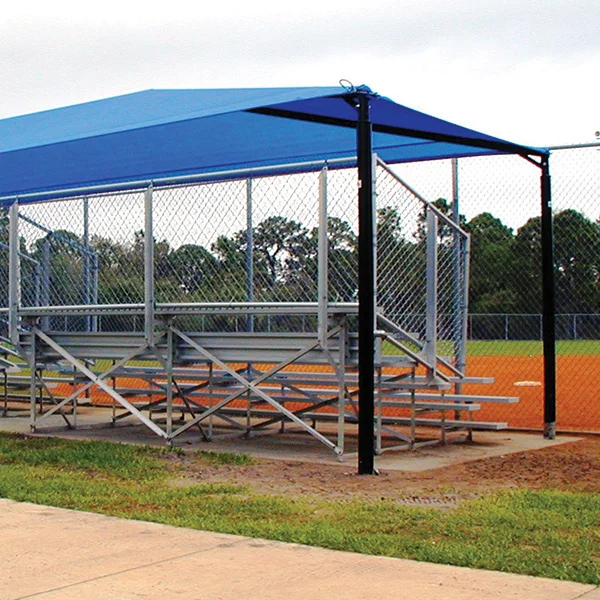 Baseball dugout shelter with blue roof and metal bleachers.