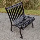 Black metal park bench on paved surface.