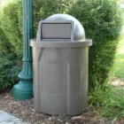 Gray outdoor trash can near greenery.