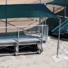 Outdoor bleachers with green canopies and metal railings.