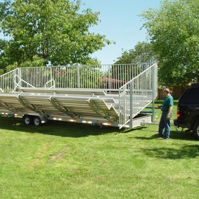 speedy108larryunfolding A man standing next to a large metal ramp trailer on grass.
